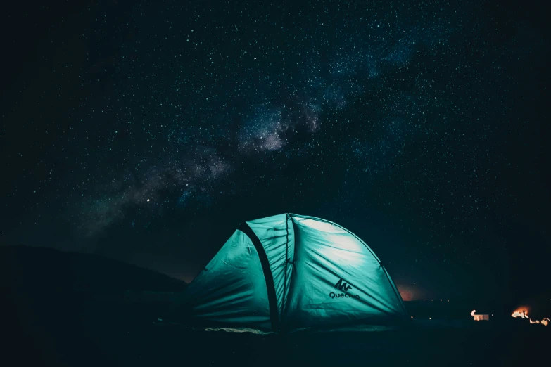 a tent under the night sky with stars and light clouds