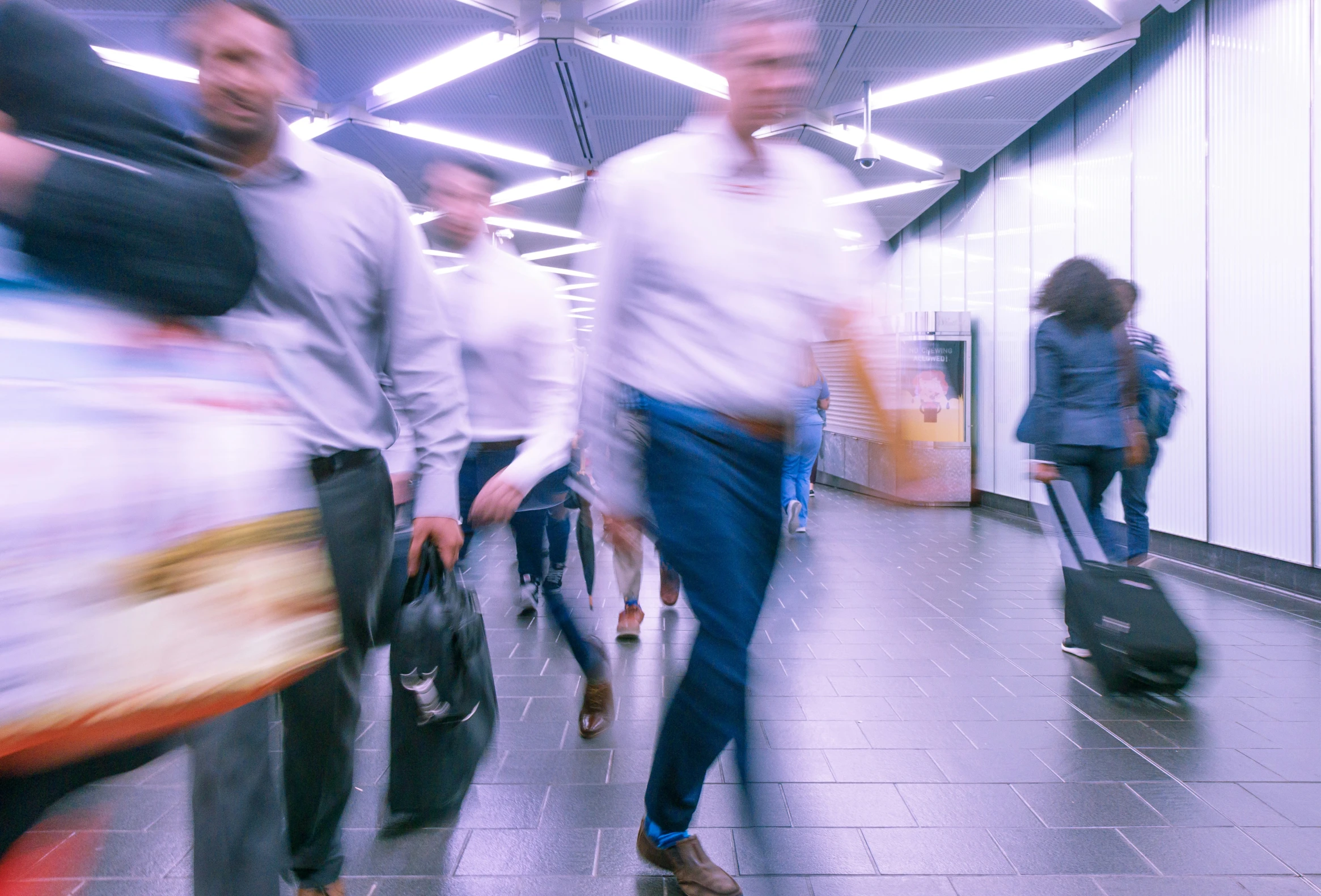 people walk through a moving subway area holding their luggage