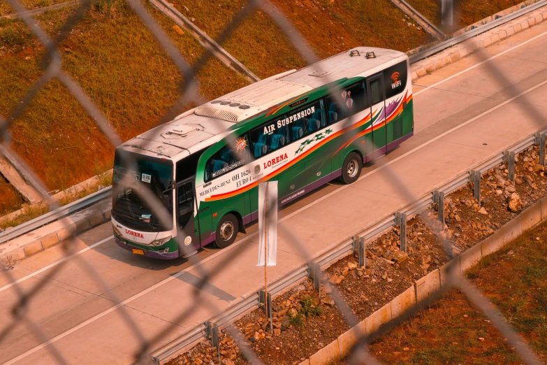 the green and white bus is on the road