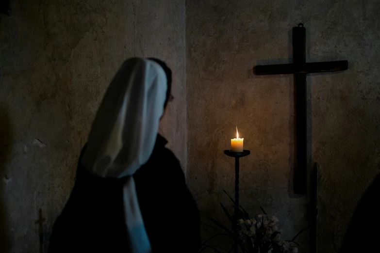 an image of a nun in the dark with a candle