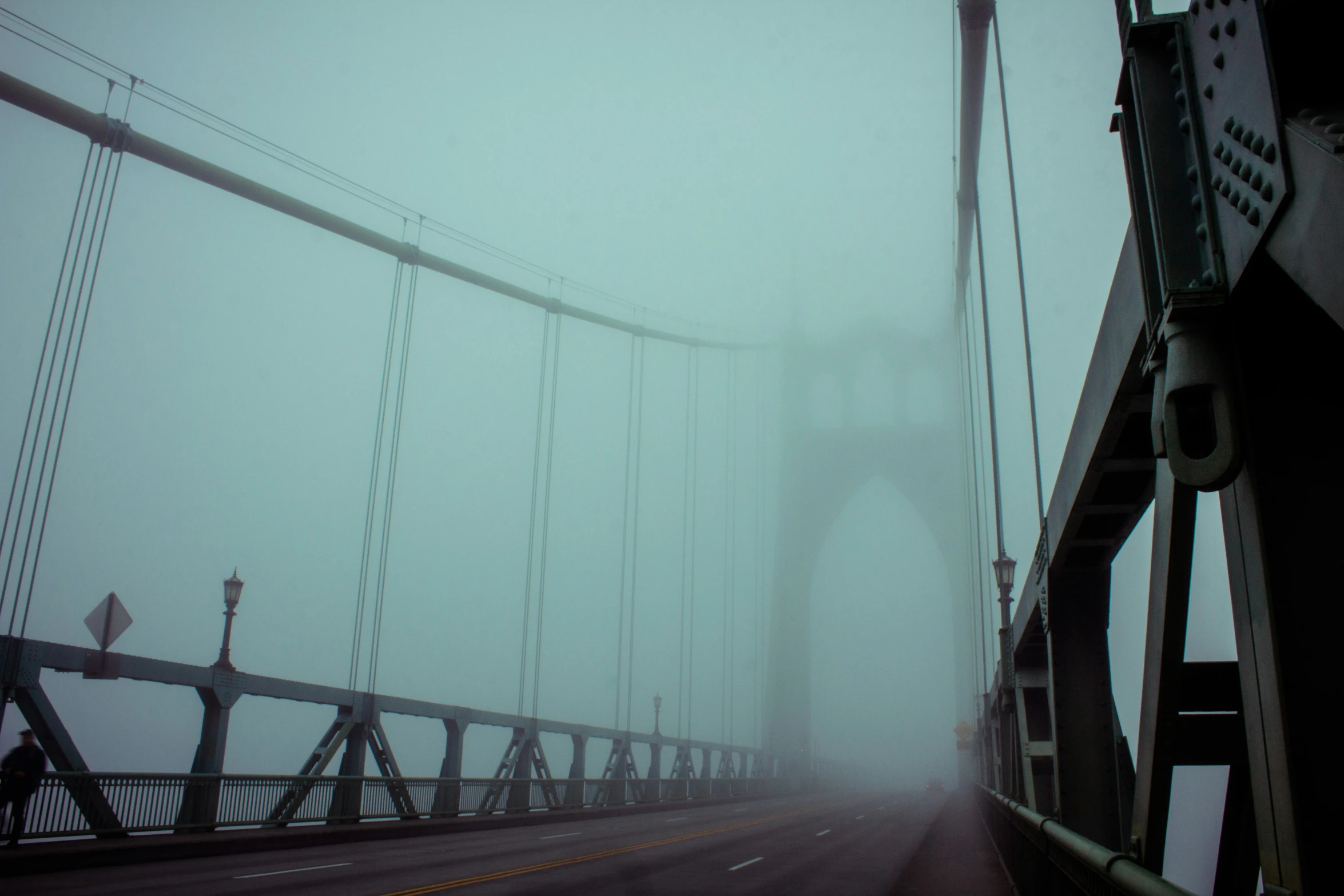 two people crossing the bridge in the fog