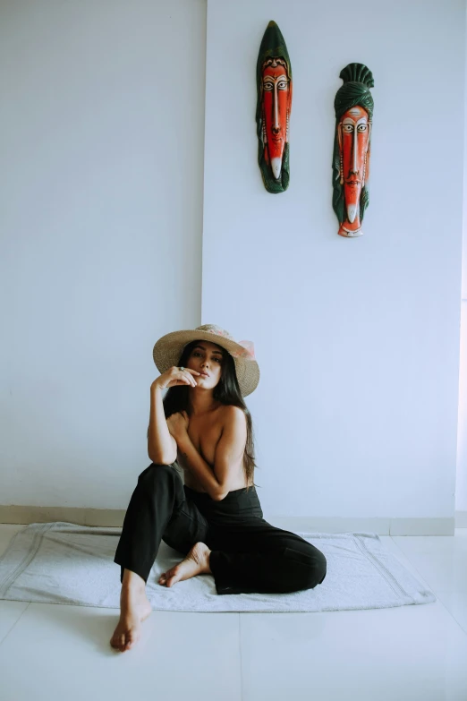 a girl in black is sitting on a white towel and some wall sculptures