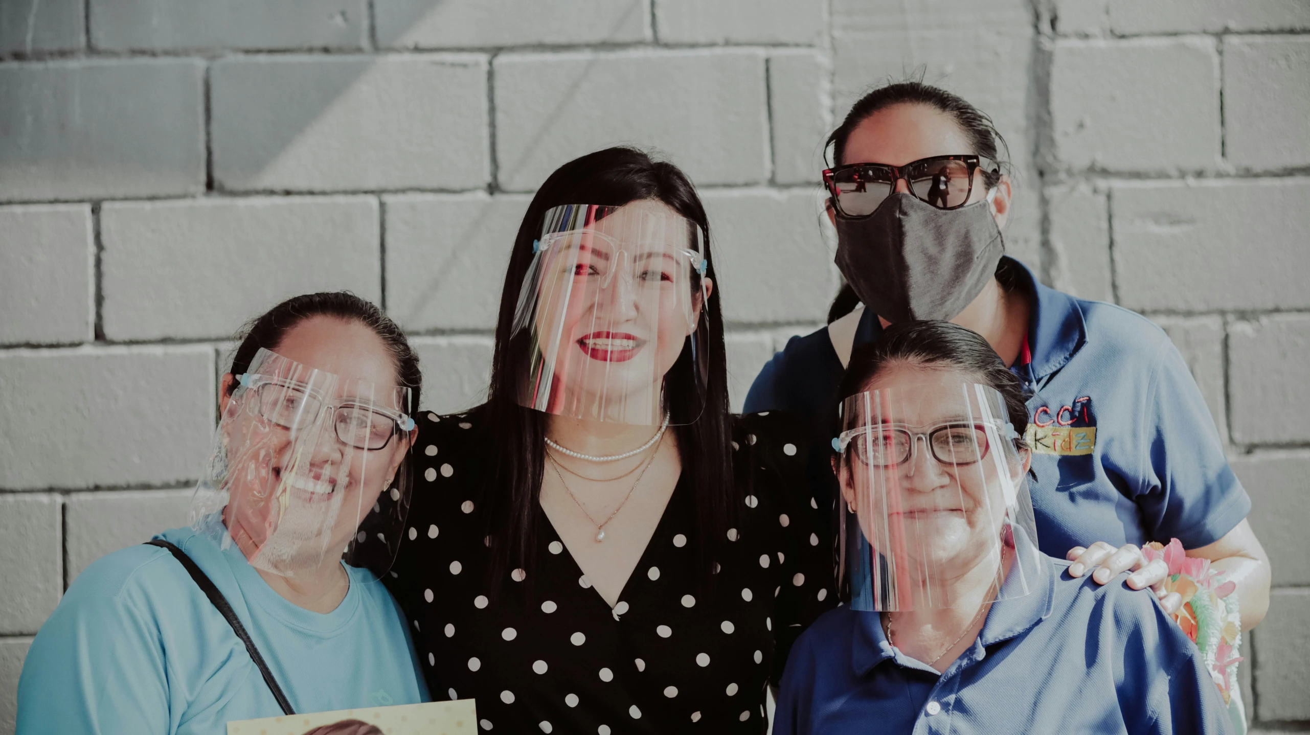 four people pose with their face covered with plastic wrap