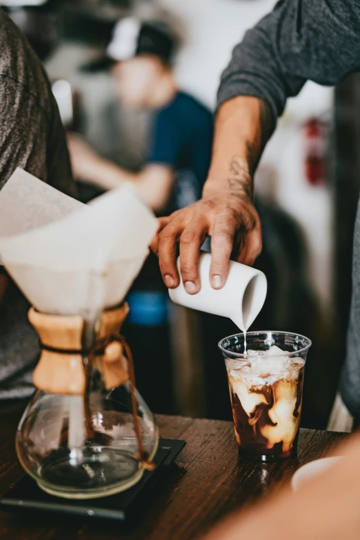 person pouring ice coffee into a glass