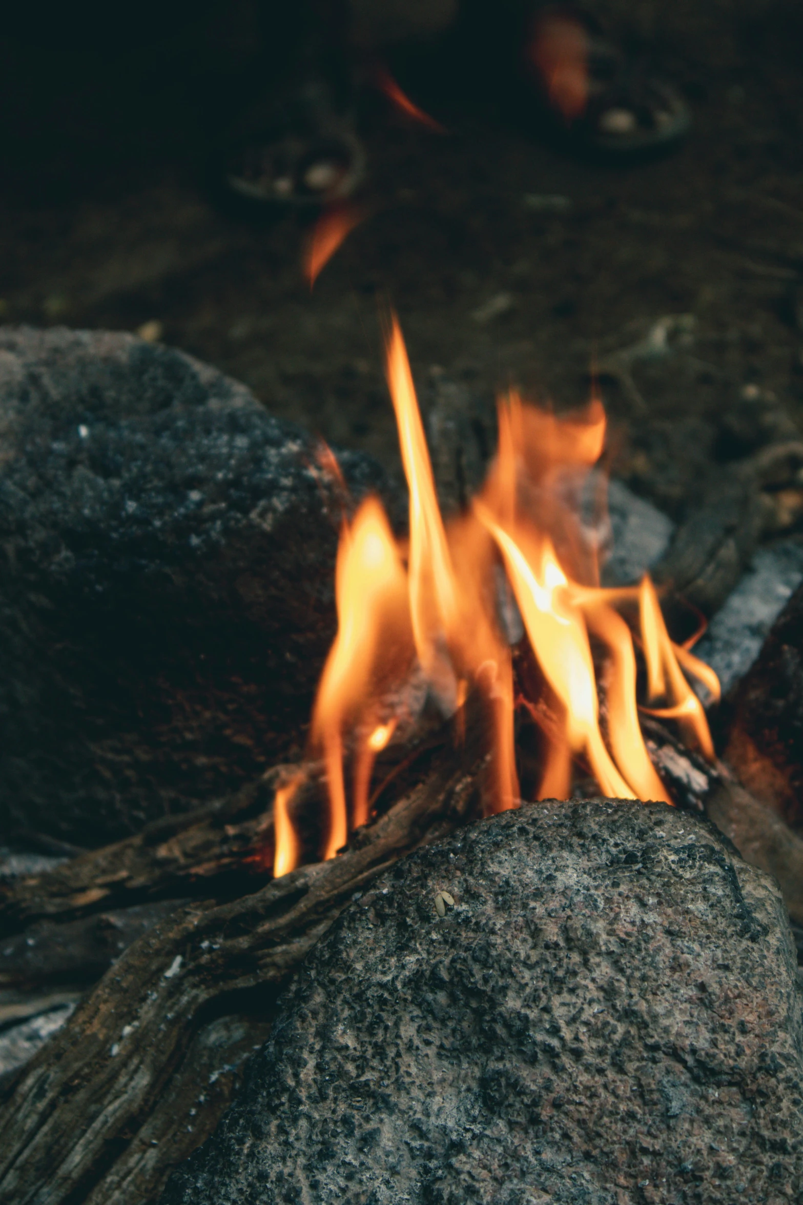 fire coming out of a stone next to a forest