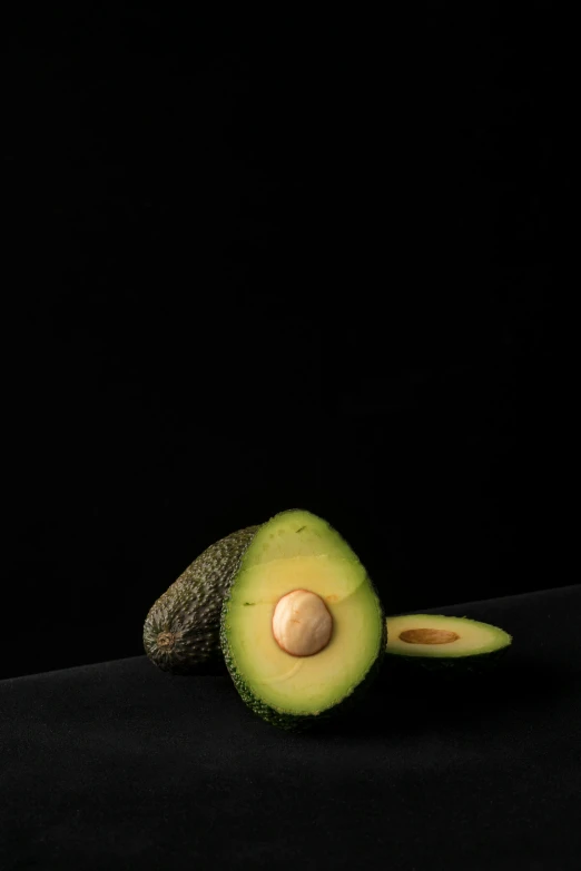 an avocado cut in half on a black surface