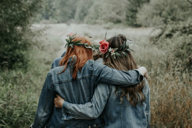 two women hugging each other in front of some trees