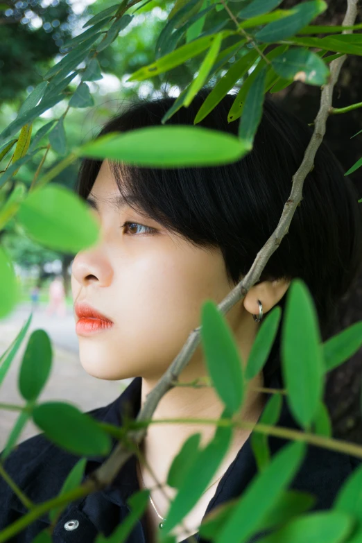 asian girl looking out from between leaves of a tree