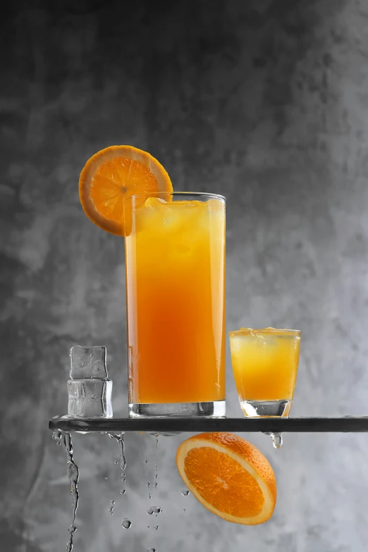 two oranges are on a metal shelf next to juice glasses