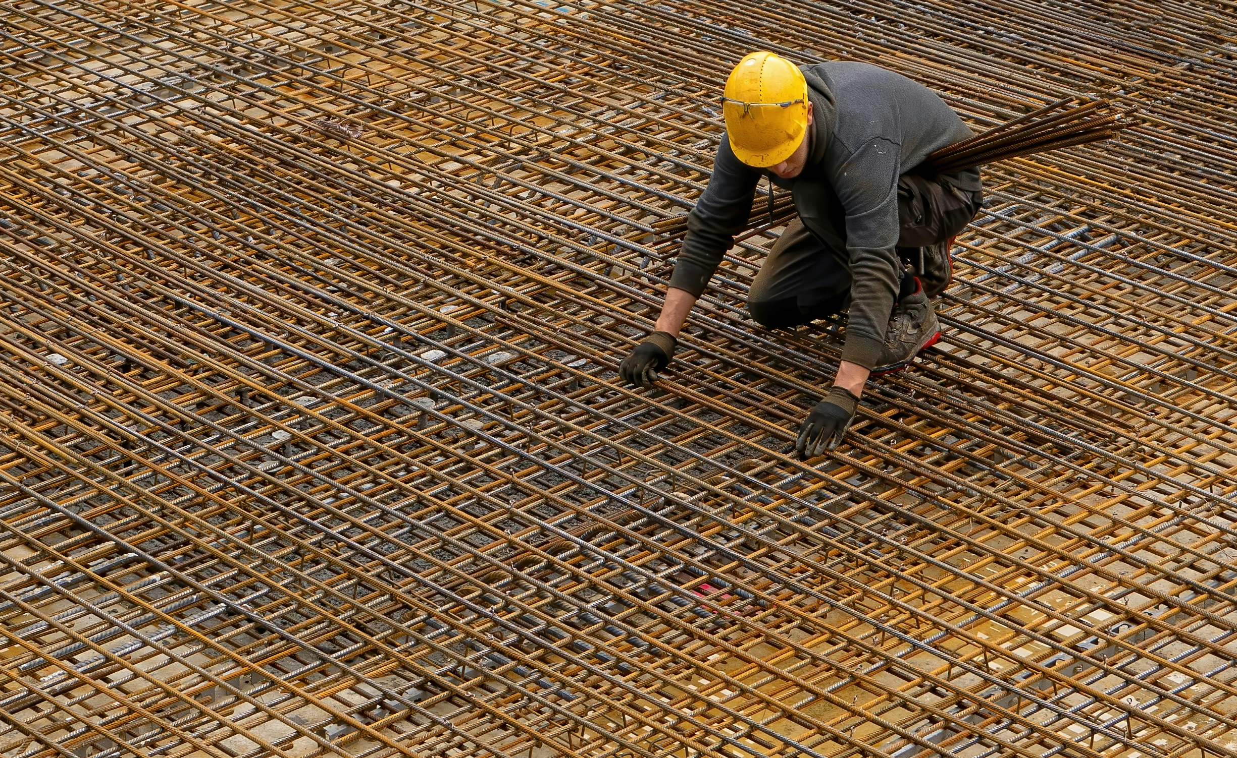 a man wearing a yellow safety helmet and working on an open steel grating