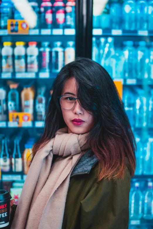 a woman with glasses standing in front of a shelf of drinks