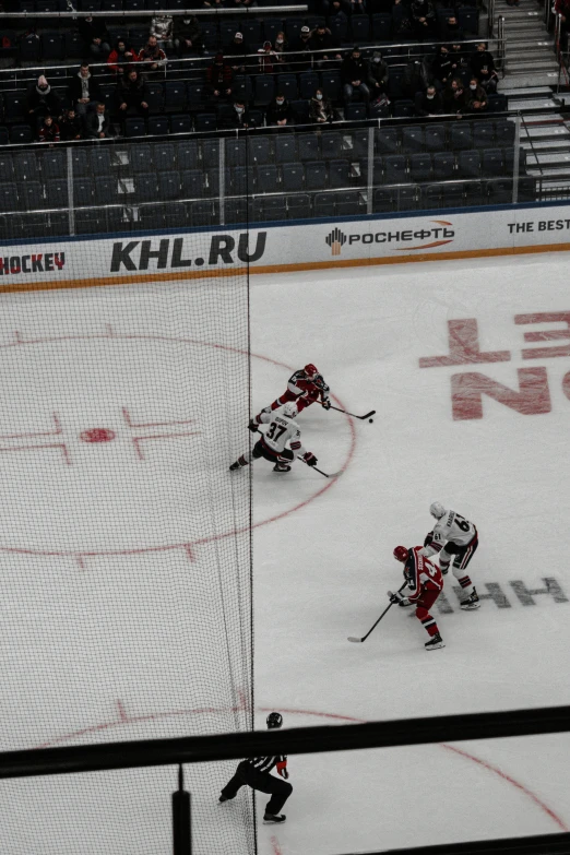 two hockey players in front of a net and the referee behind the net