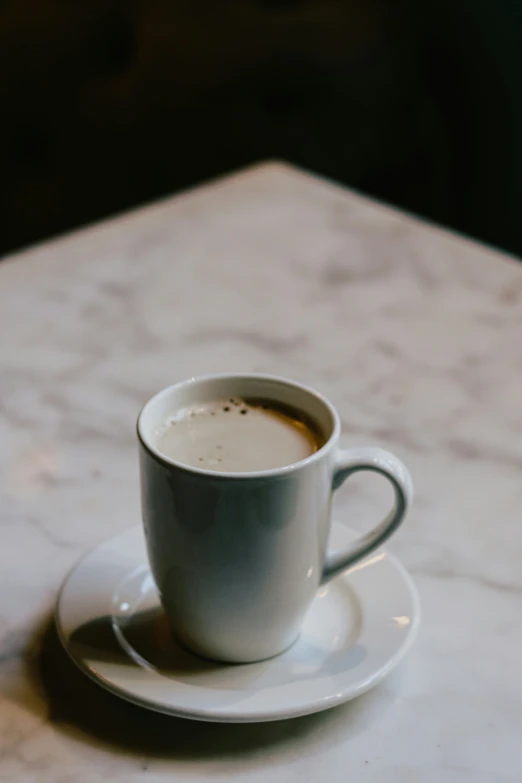 a cup of coffee on a saucer on a marble table