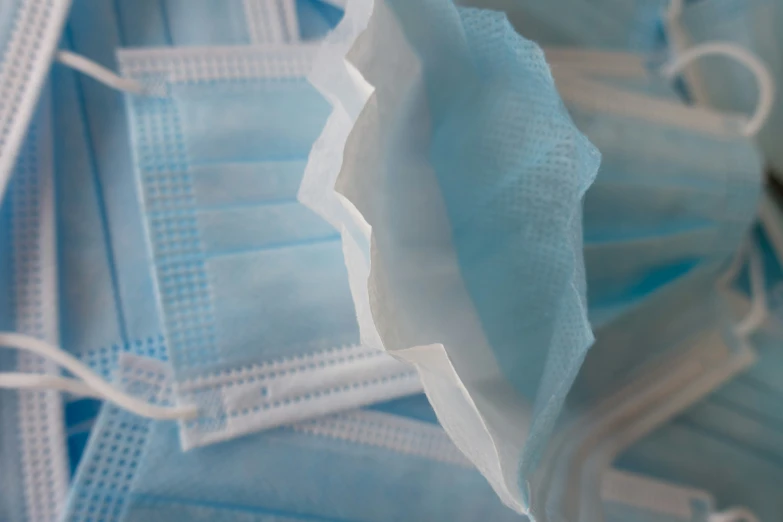 a pile of surgical masks with blue strings