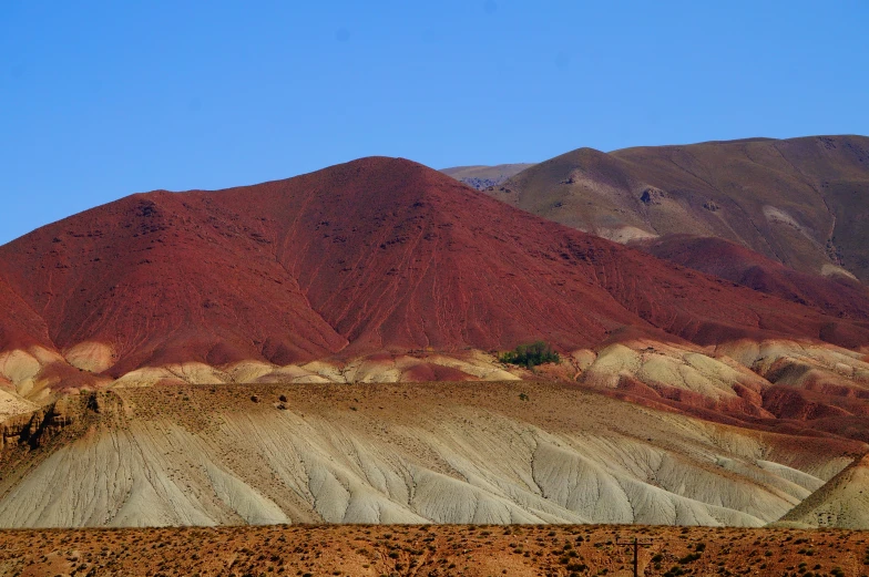 a plowed area and mountains that have red dirt on top
