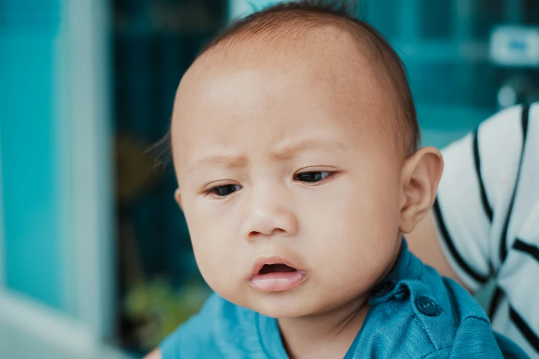 a baby looks sad as someone holds it up in front of him