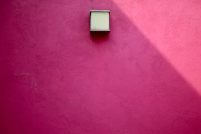 a pink wall with a white box on the side