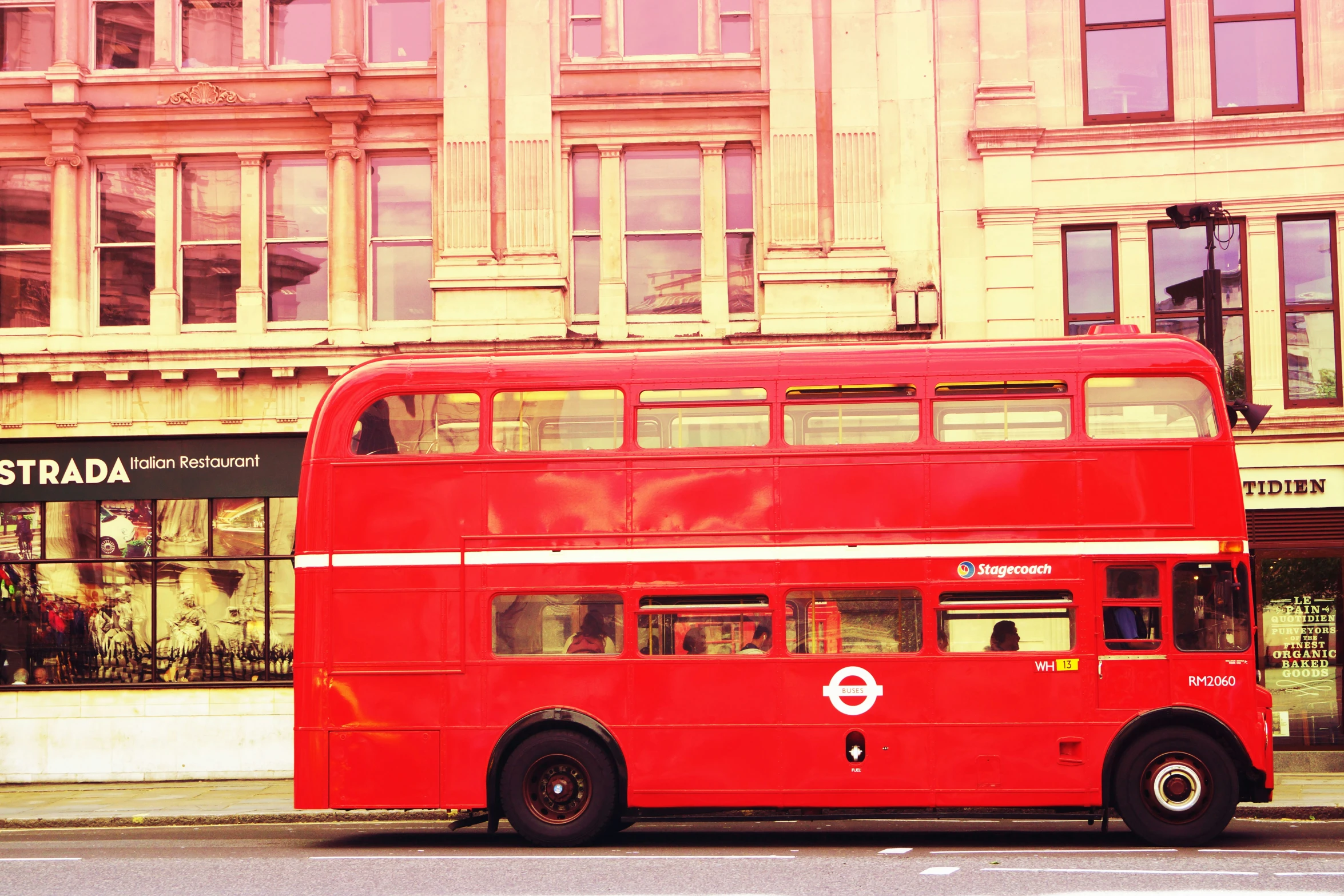 a large red bus is parked outside of a tall building