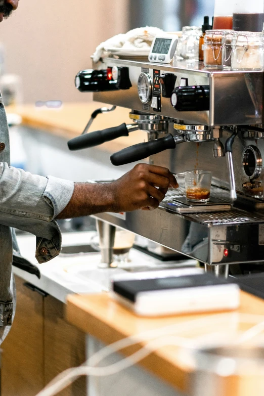 a person standing over a counter next to a coffee cup