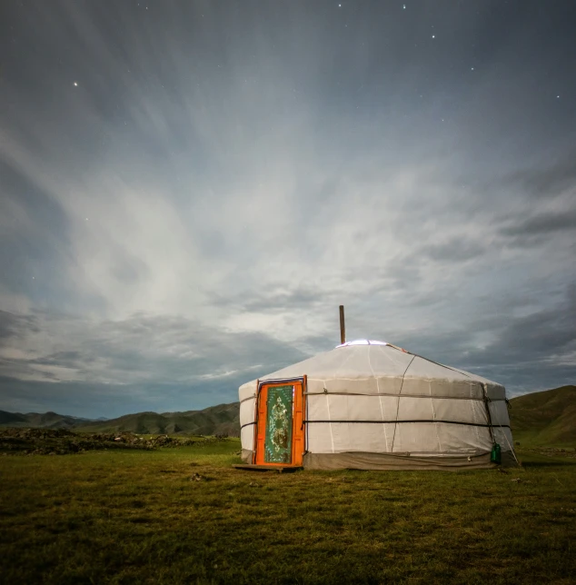 a yurt built from tarps on top of green field