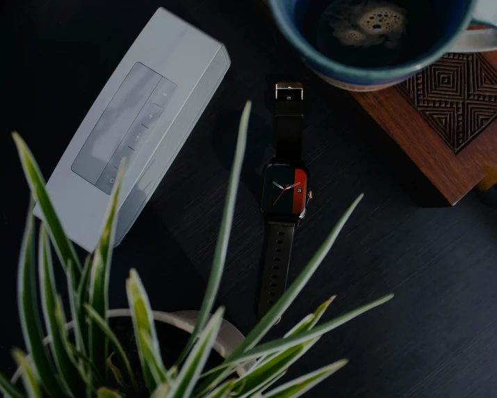 a closeup of a watch on a desk with a cup