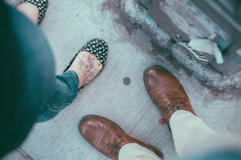 three people with brown shoes on standing in the street