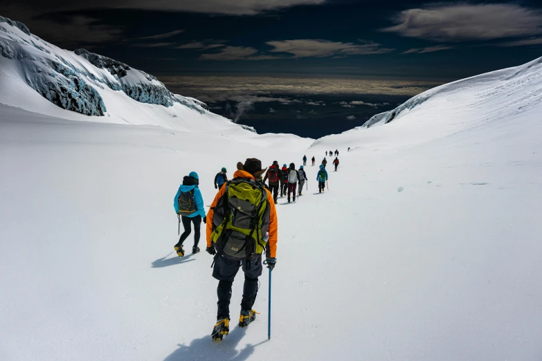 several skiers are seen traveling uphill in the mountains