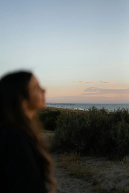 a woman watching a kite being flown in the sky