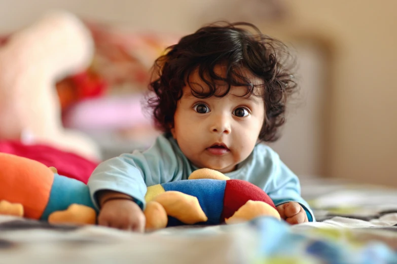 a little  playing with toys on a bed