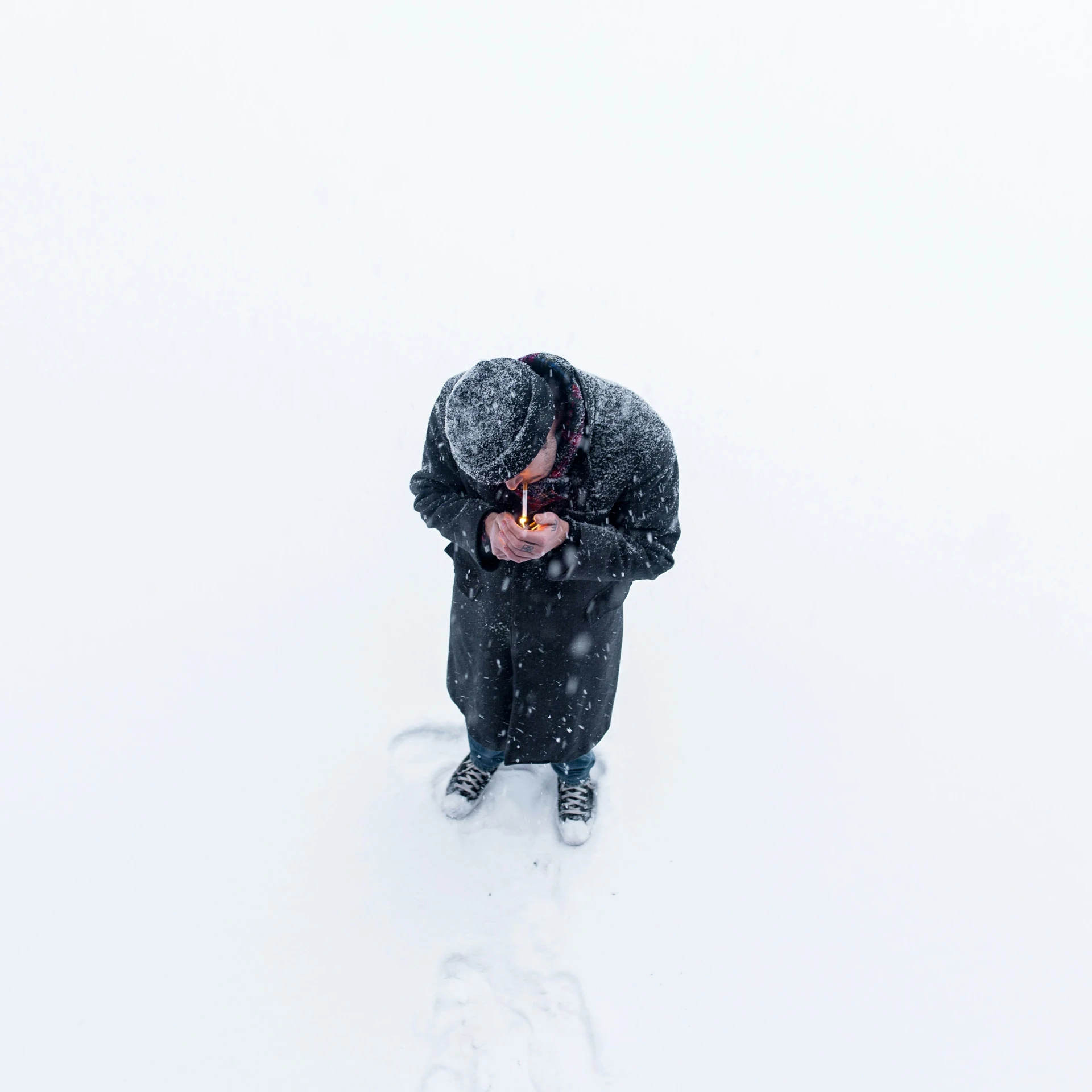 person in black snowsuit holding food with hand while standing on skis