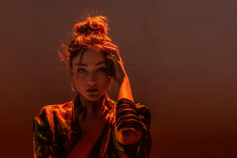 a woman with her hand on her head wearing a topknot