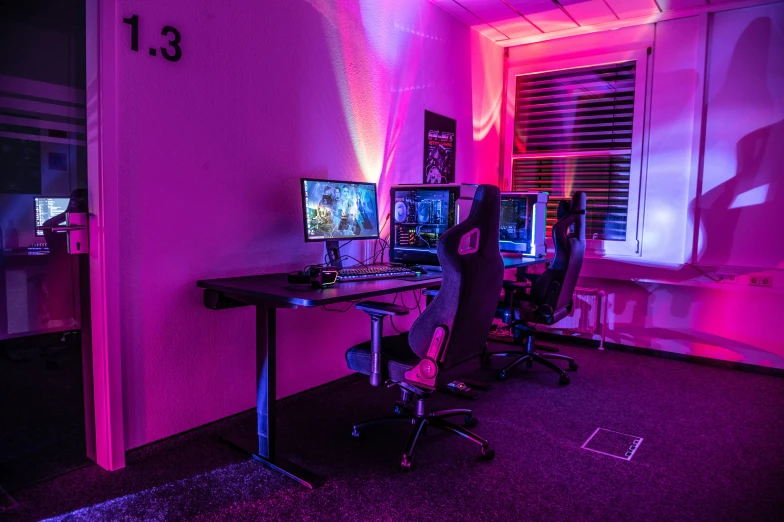 a dark room with two computers on a black desk