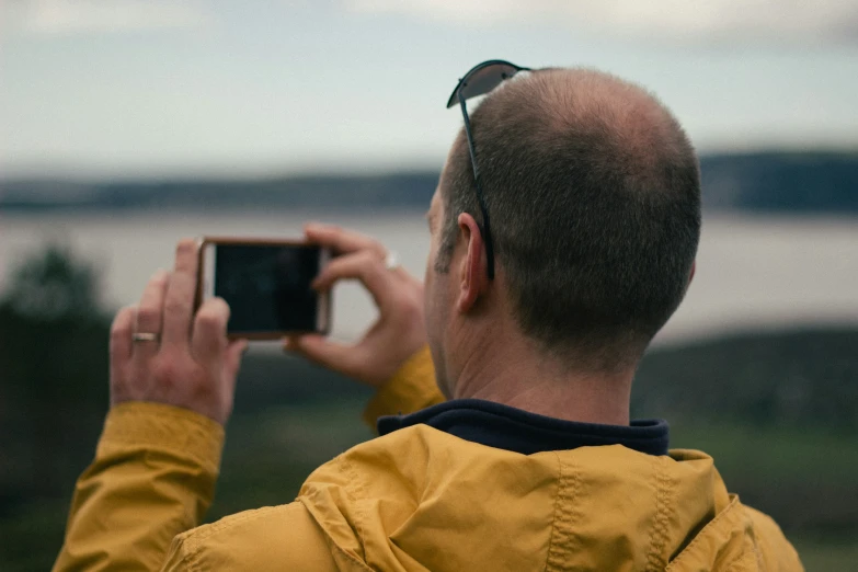 a man holding up a camera while standing on top of a grass field