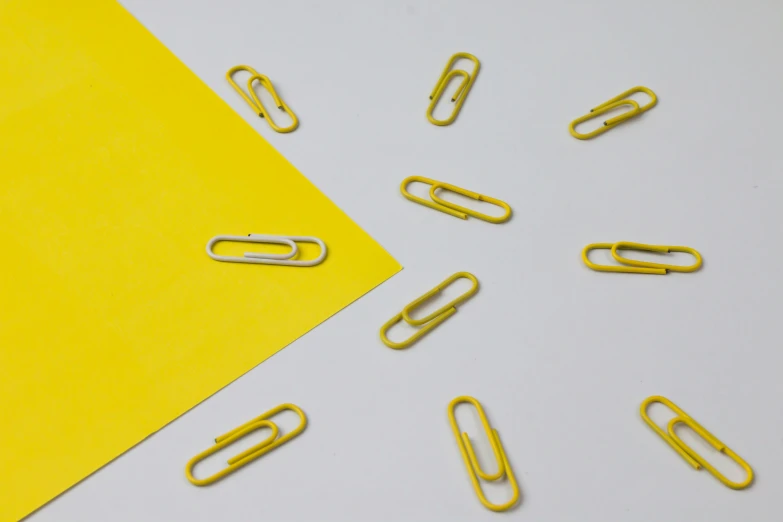 some yellow paper clips and a piece of yellow paper