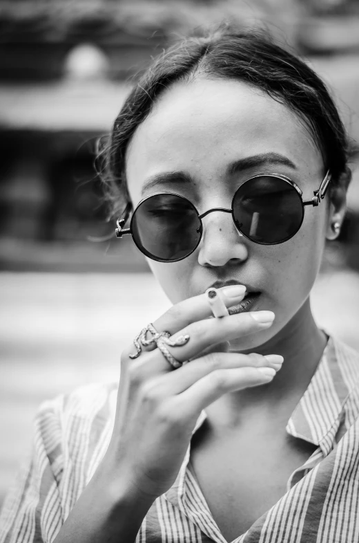 the young woman is dressed in sunglasses and chewing on a piece of fruit