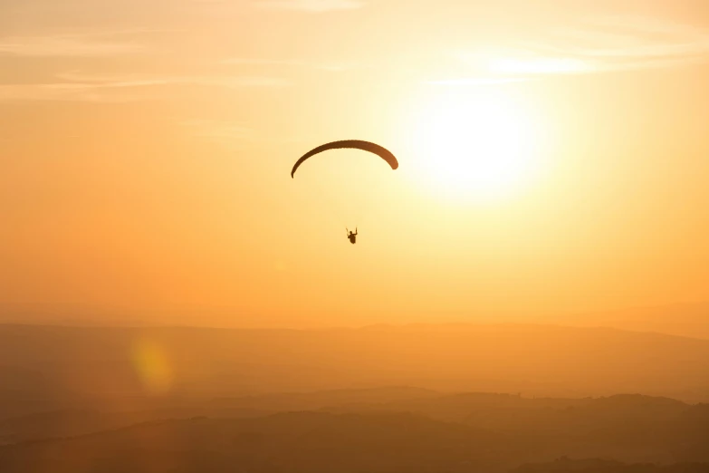 the sun is setting as the parasailer flies in the sky