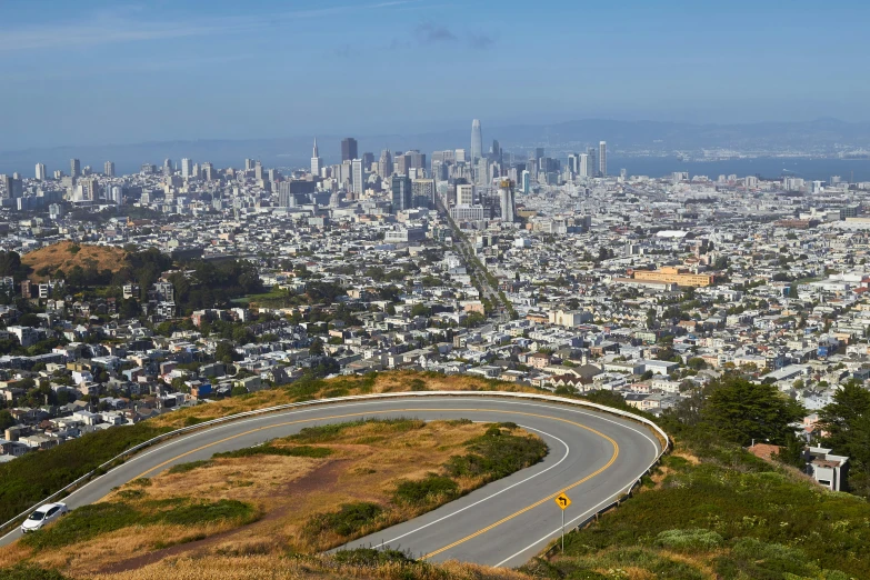 an empty road and highway with the view of a large city in the distance