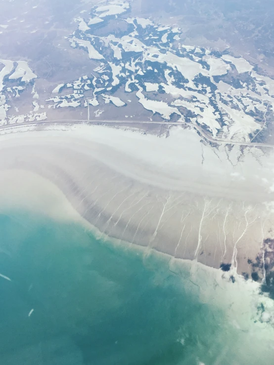 view from airplane window looking down onto an ocean and sandy beach area