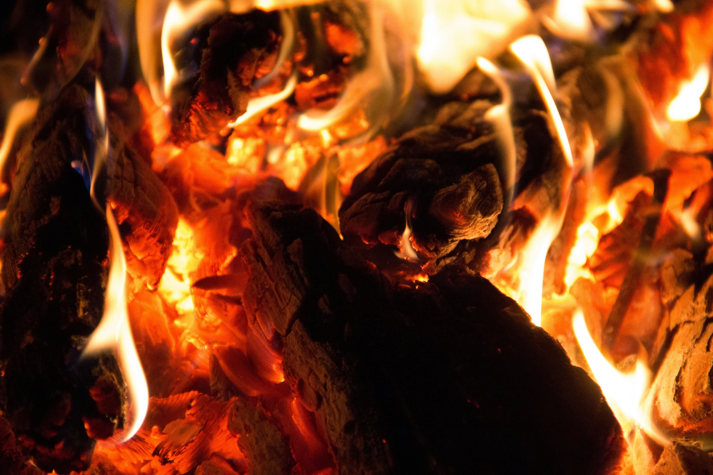 a burning fireplace filled with wood and orange flame