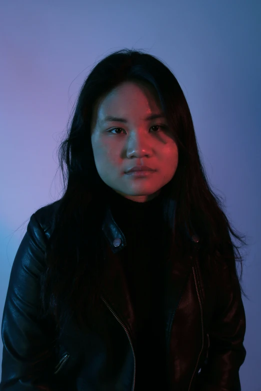 a woman with long black hair and black jacket sitting down