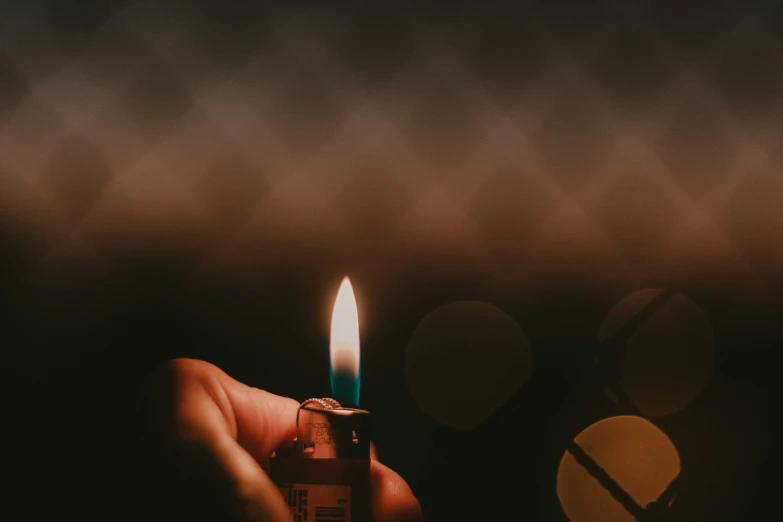 a person holding a lit lighter in their hand