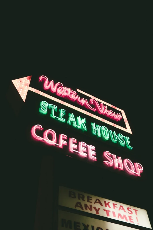 a restaurant sign sitting up against a dark night sky