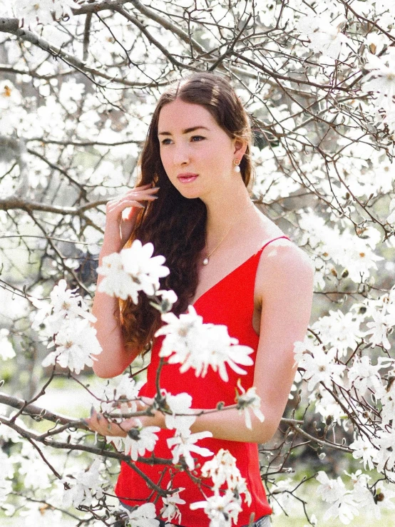 a woman wearing a dress and standing under a tree