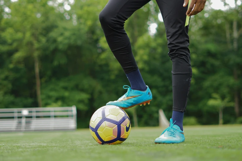 a man wearing a blue and yellow soccer shoes on a soccer ball