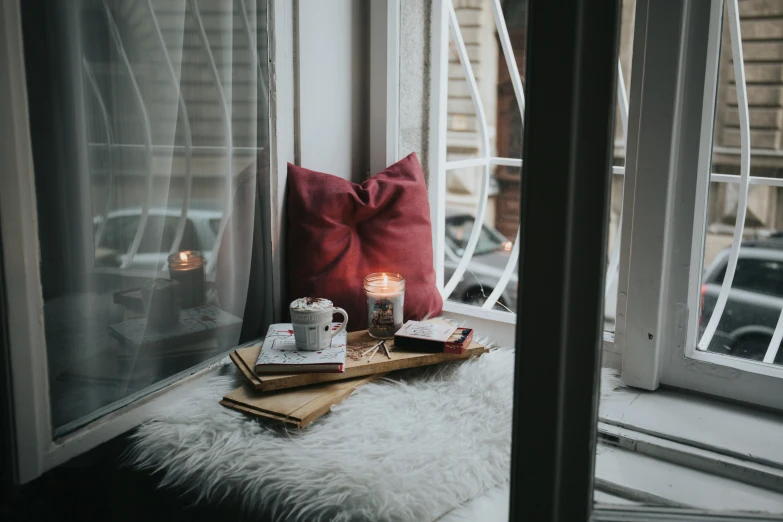 candles, books and other objects are displayed on the window sill