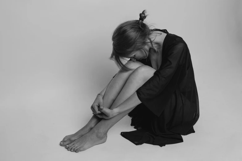 a woman with her knees down sitting on the ground