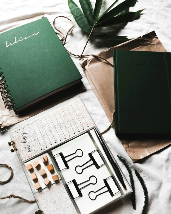 two books and some green paper on a bed