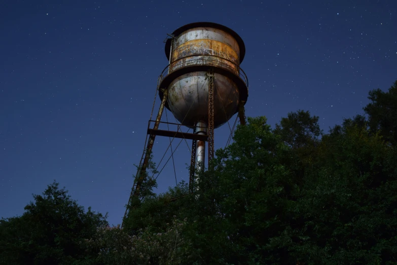 a large rusted water tower near trees