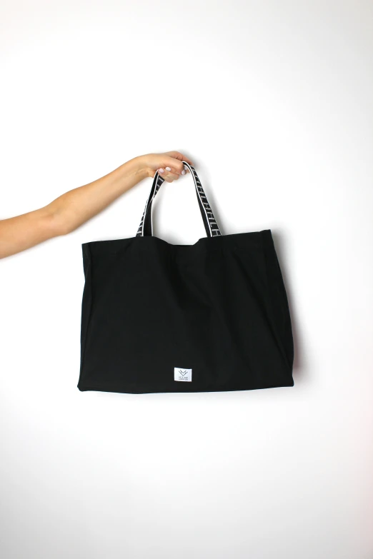 a hand holding a black bag with the bottom zipper closed