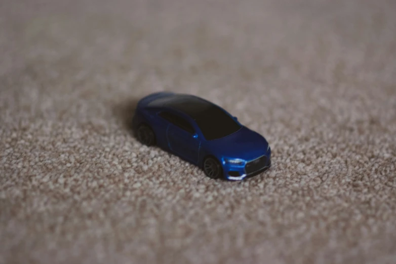 a blue toy car sitting on top of carpet